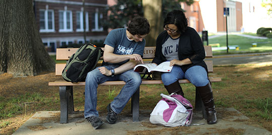 N.C. A&T students sitting on a bench on campus in front on Noble Hall